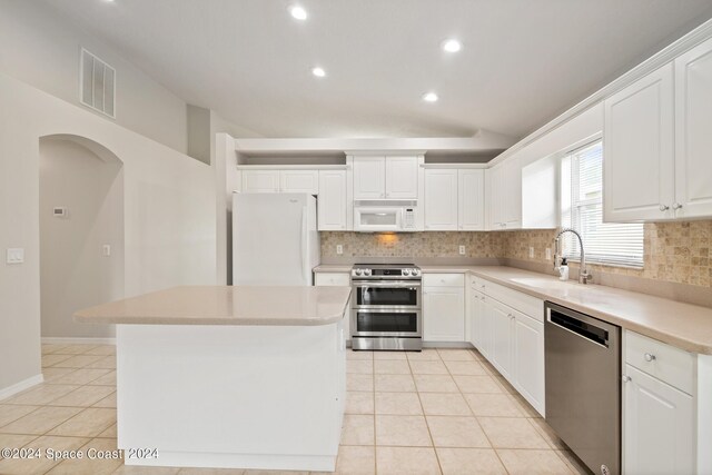 kitchen with appliances with stainless steel finishes, backsplash, sink, a center island, and light tile patterned flooring