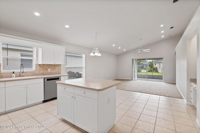 kitchen featuring backsplash, decorative light fixtures, stainless steel dishwasher, white cabinets, and lofted ceiling