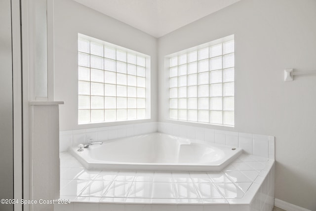 bathroom featuring a wealth of natural light and tiled bath