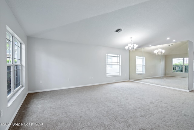 carpeted spare room featuring a notable chandelier