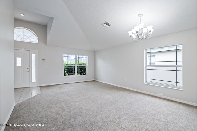 carpeted entrance foyer with a textured ceiling, vaulted ceiling, and an inviting chandelier