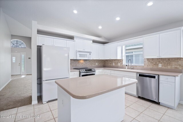 kitchen featuring a center island, appliances with stainless steel finishes, tasteful backsplash, white cabinetry, and lofted ceiling