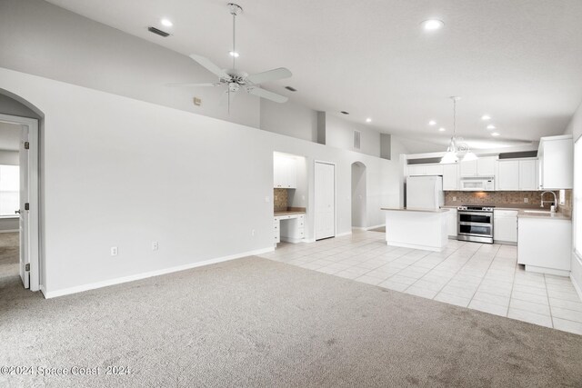 unfurnished living room with ceiling fan, sink, a high ceiling, and light carpet