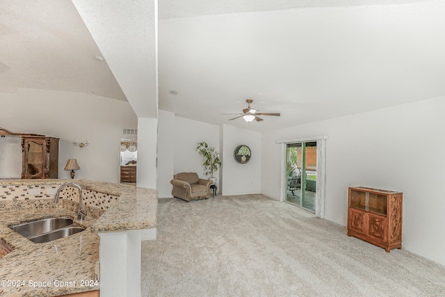 kitchen with ceiling fan, light carpet, light stone countertops, sink, and lofted ceiling