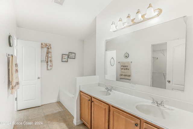 bathroom with dual vanity, a tub to relax in, and tile patterned flooring