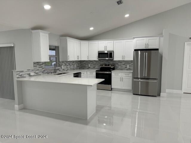 kitchen featuring a peninsula, white cabinetry, vaulted ceiling, light countertops, and appliances with stainless steel finishes