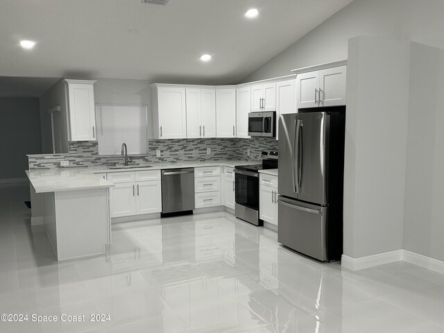 kitchen featuring appliances with stainless steel finishes, a peninsula, light countertops, white cabinetry, and a sink