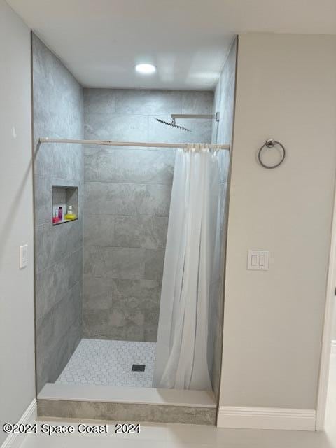 bathroom featuring tiled shower and baseboards