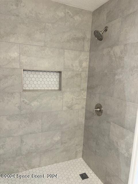 bathroom featuring a tile shower and a textured ceiling