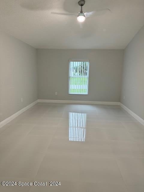 spare room featuring ceiling fan, baseboards, and light tile patterned floors