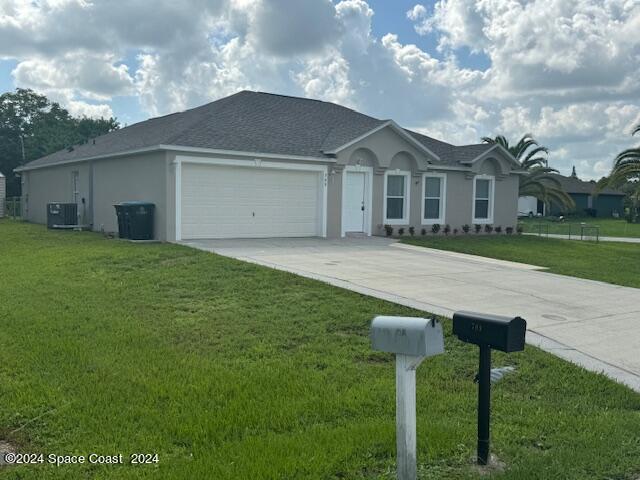 ranch-style house with central air condition unit, a garage, and a front lawn