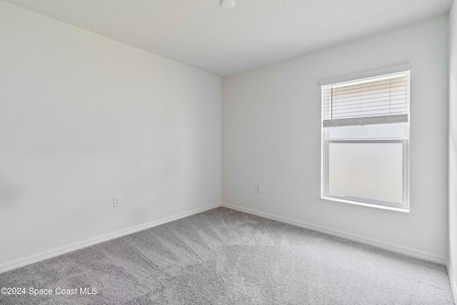 unfurnished room with carpet and baseboards