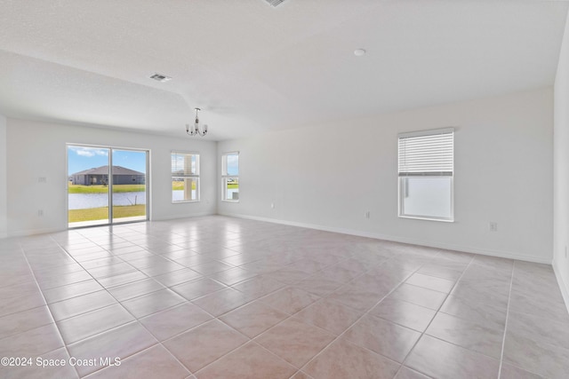 spare room with a notable chandelier, visible vents, light tile patterned flooring, a textured ceiling, and baseboards