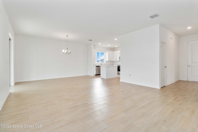 unfurnished living room featuring light hardwood / wood-style flooring and an inviting chandelier