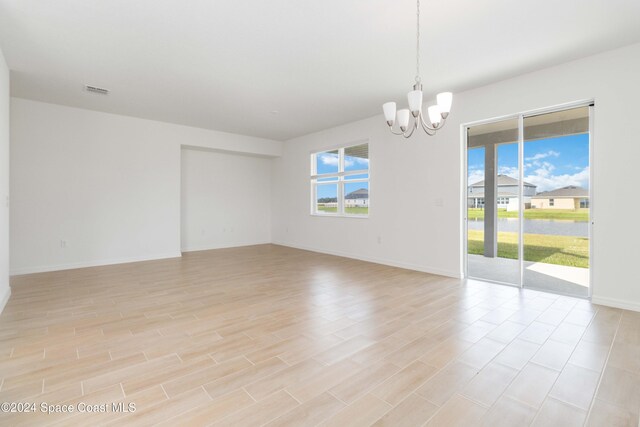 empty room featuring light hardwood / wood-style flooring and an inviting chandelier