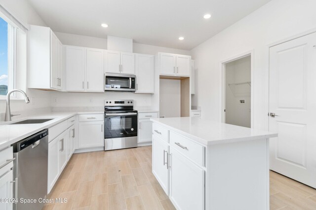 kitchen with sink, white cabinets, stainless steel appliances, and a kitchen island