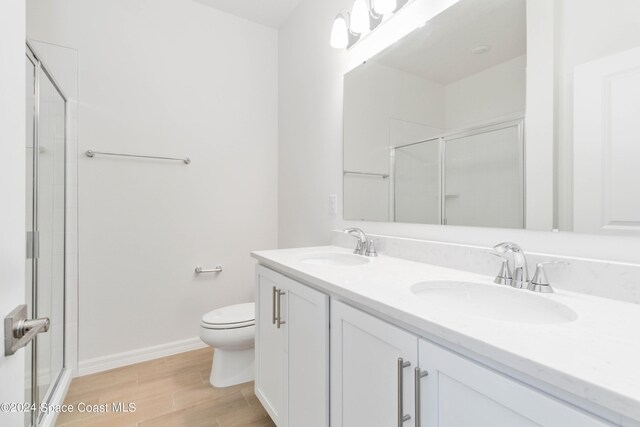 bathroom featuring vanity, toilet, wood-type flooring, and a shower with shower door