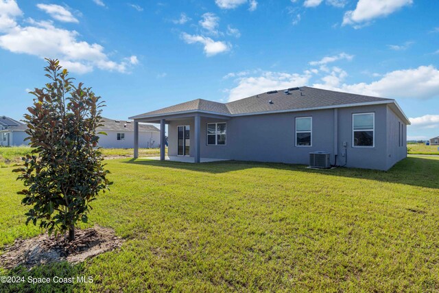 rear view of house with a yard and cooling unit