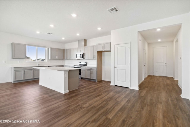 kitchen featuring gray cabinets, a kitchen island, dark wood-type flooring, and appliances with stainless steel finishes