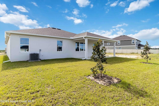 rear view of property with cooling unit and a lawn