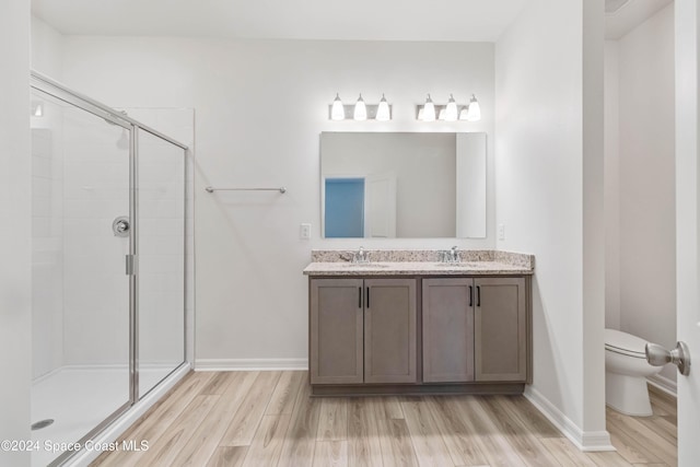 bathroom with hardwood / wood-style floors, vanity, toilet, and walk in shower