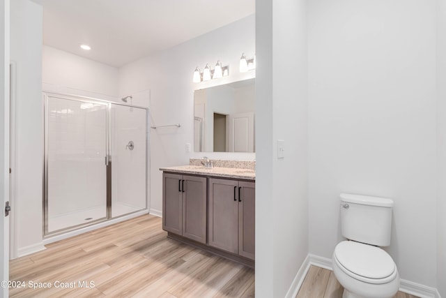 bathroom with hardwood / wood-style flooring, vanity, toilet, and a shower with shower door