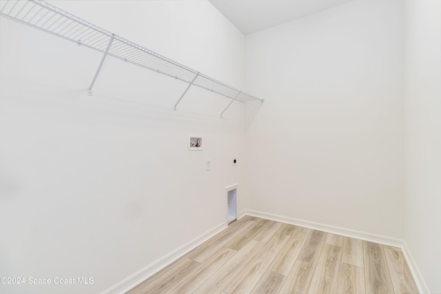 laundry area featuring electric dryer hookup, hookup for a washing machine, and light hardwood / wood-style flooring