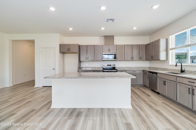 kitchen with a center island, sink, appliances with stainless steel finishes, and light hardwood / wood-style flooring