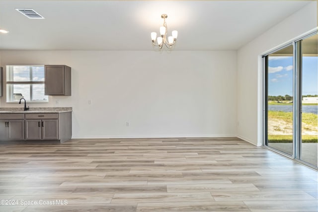 interior space with light hardwood / wood-style floors, sink, and an inviting chandelier