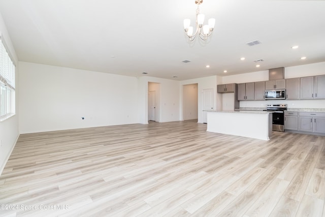 kitchen with light wood-type flooring, gray cabinetry, stainless steel appliances, an inviting chandelier, and a center island