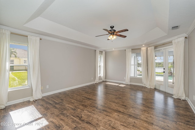 empty room with ceiling fan, a tray ceiling, and hardwood / wood-style floors