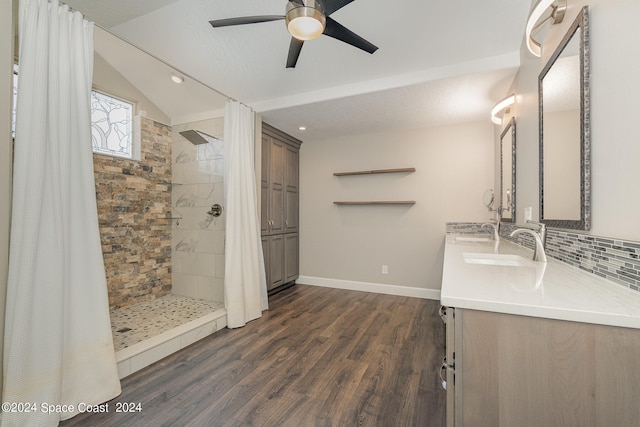 bathroom with backsplash, hardwood / wood-style flooring, vaulted ceiling, a shower with shower curtain, and vanity