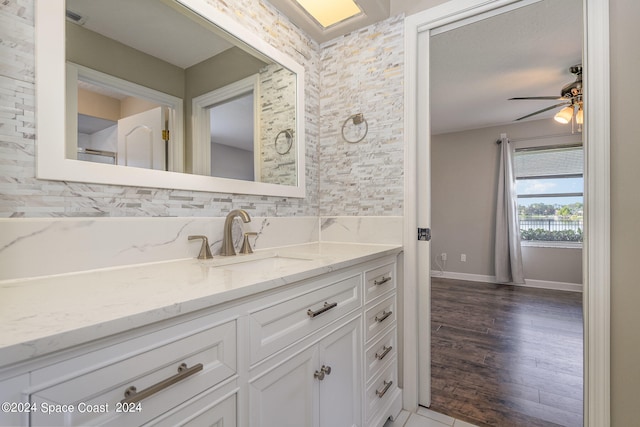 bathroom with hardwood / wood-style floors, tasteful backsplash, ceiling fan, and vanity