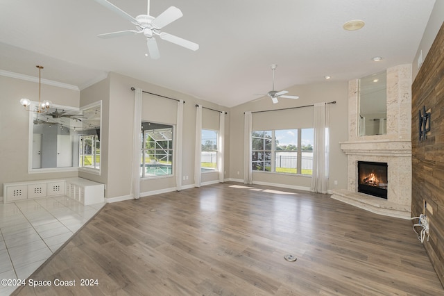 unfurnished living room with a fireplace, ceiling fan with notable chandelier, a healthy amount of sunlight, and hardwood / wood-style flooring