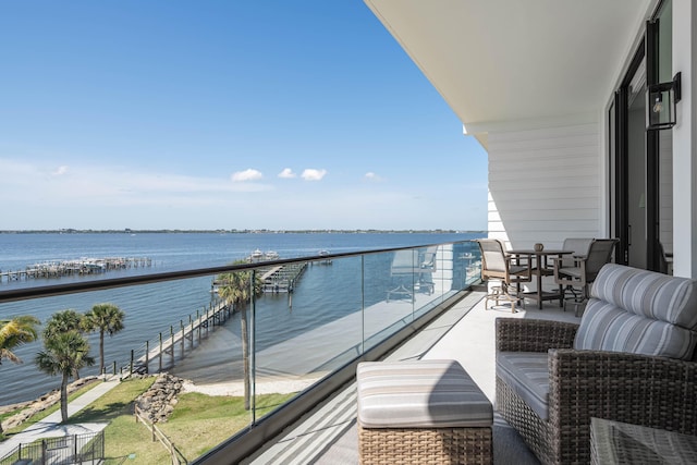 balcony with a water view and outdoor dining space