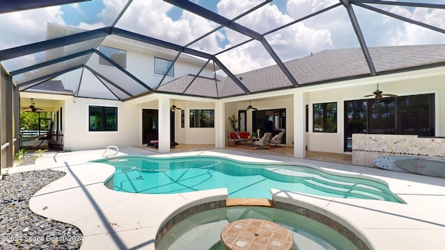 view of swimming pool with ceiling fan, glass enclosure, a patio, and an in ground hot tub