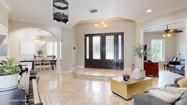 tiled entrance foyer featuring ceiling fan with notable chandelier, ornamental molding, and ornate columns