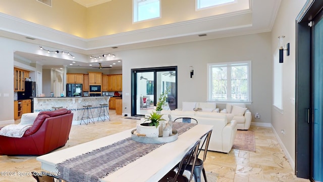 dining space featuring a high ceiling, rail lighting, a tray ceiling, light tile patterned floors, and crown molding