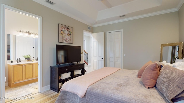 bedroom featuring ornamental molding, sink, a tray ceiling, a closet, and ensuite bathroom