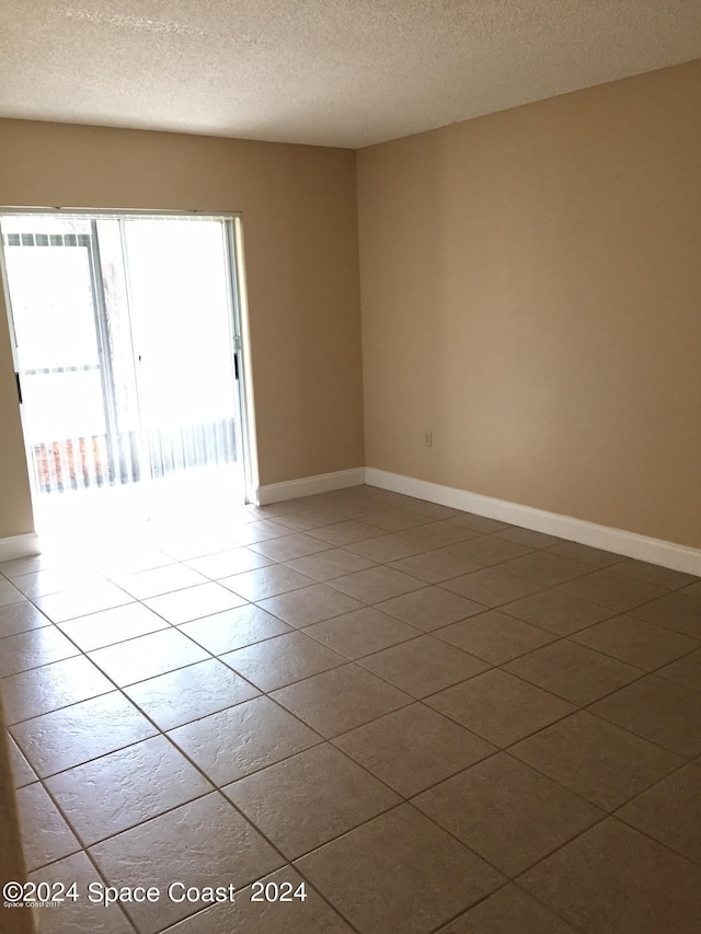 tiled empty room featuring a textured ceiling