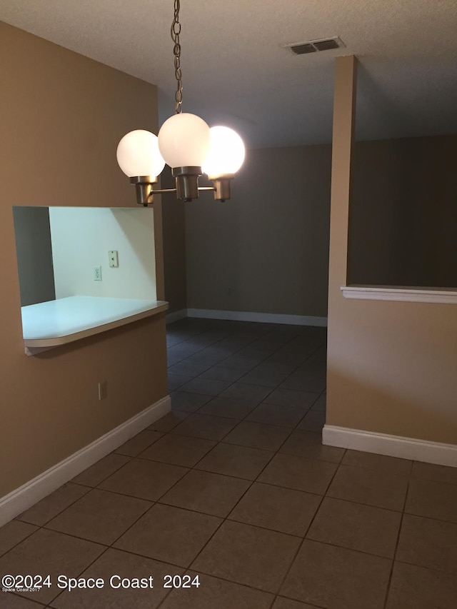 tiled empty room featuring a textured ceiling