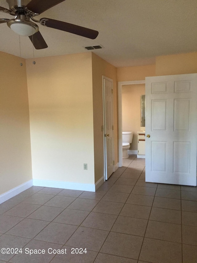 unfurnished bedroom featuring ensuite bathroom, ceiling fan, and tile patterned flooring