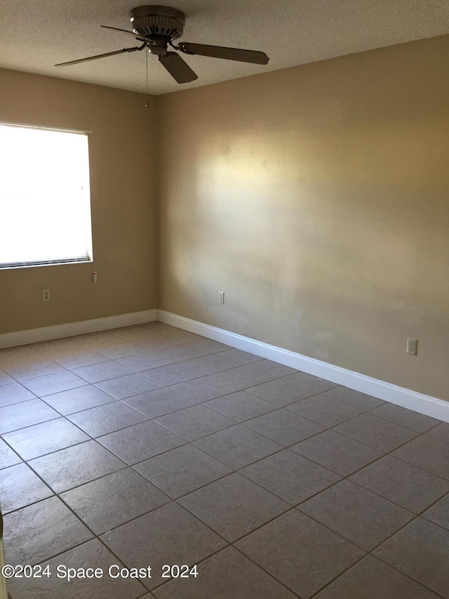 empty room with a textured ceiling, ceiling fan, and tile patterned floors