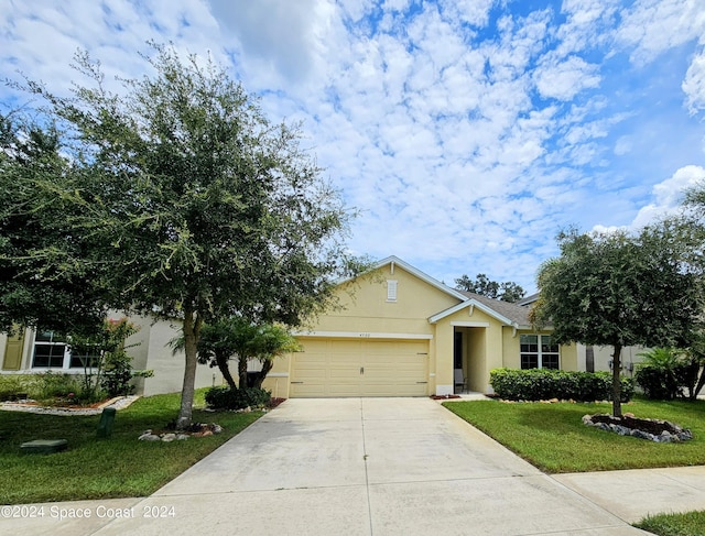 view of front of home with an attached garage, a front yard, concrete driveway, and stucco siding