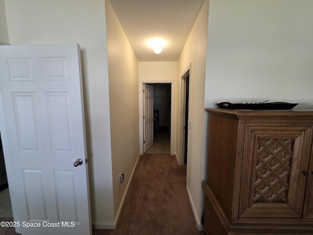 hall with carpet, a textured ceiling, and baseboards