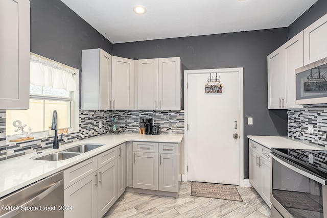 kitchen featuring sink, white cabinets, backsplash, and appliances with stainless steel finishes