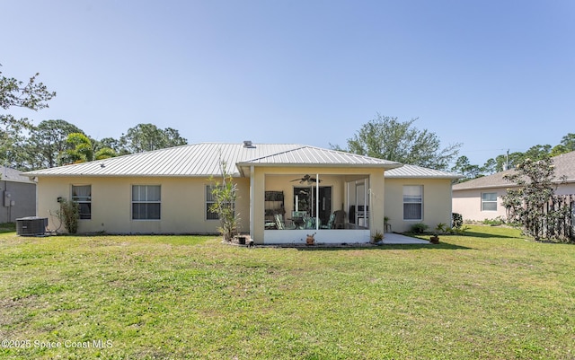 back of property with stucco siding, a yard, ceiling fan, and metal roof