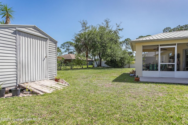 view of yard with fence, a storage shed, ceiling fan, an outdoor structure, and a sunroom