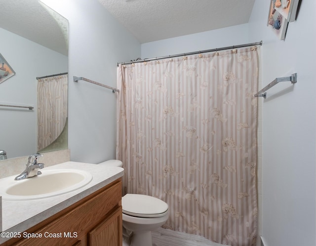 full bathroom with toilet, vanity, and a textured ceiling