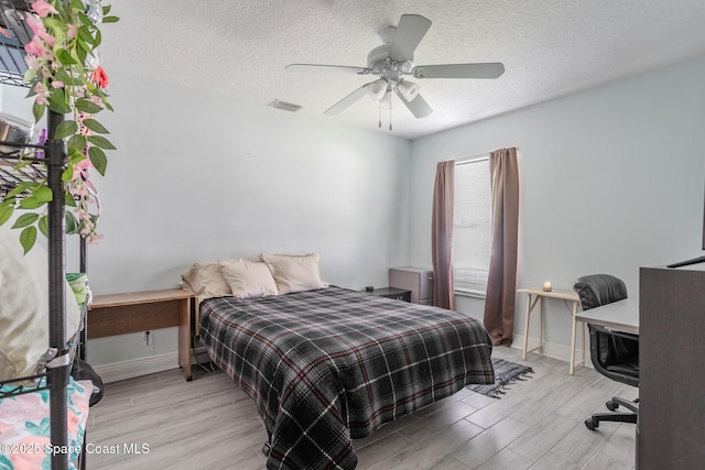 bedroom with visible vents, wood finish floors, a textured ceiling, and ceiling fan